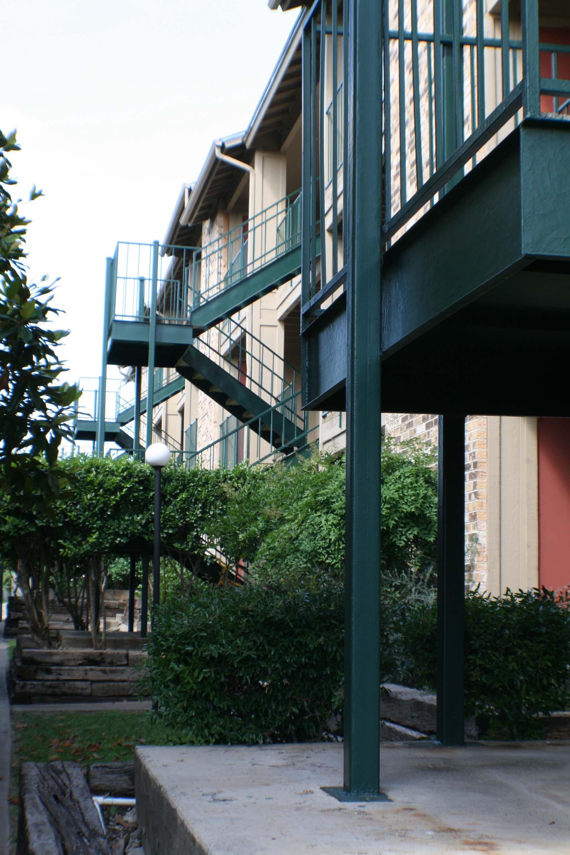 Stadium View Apartments outdoor entrances and stairs to unit, surrounded by trees and bushes.