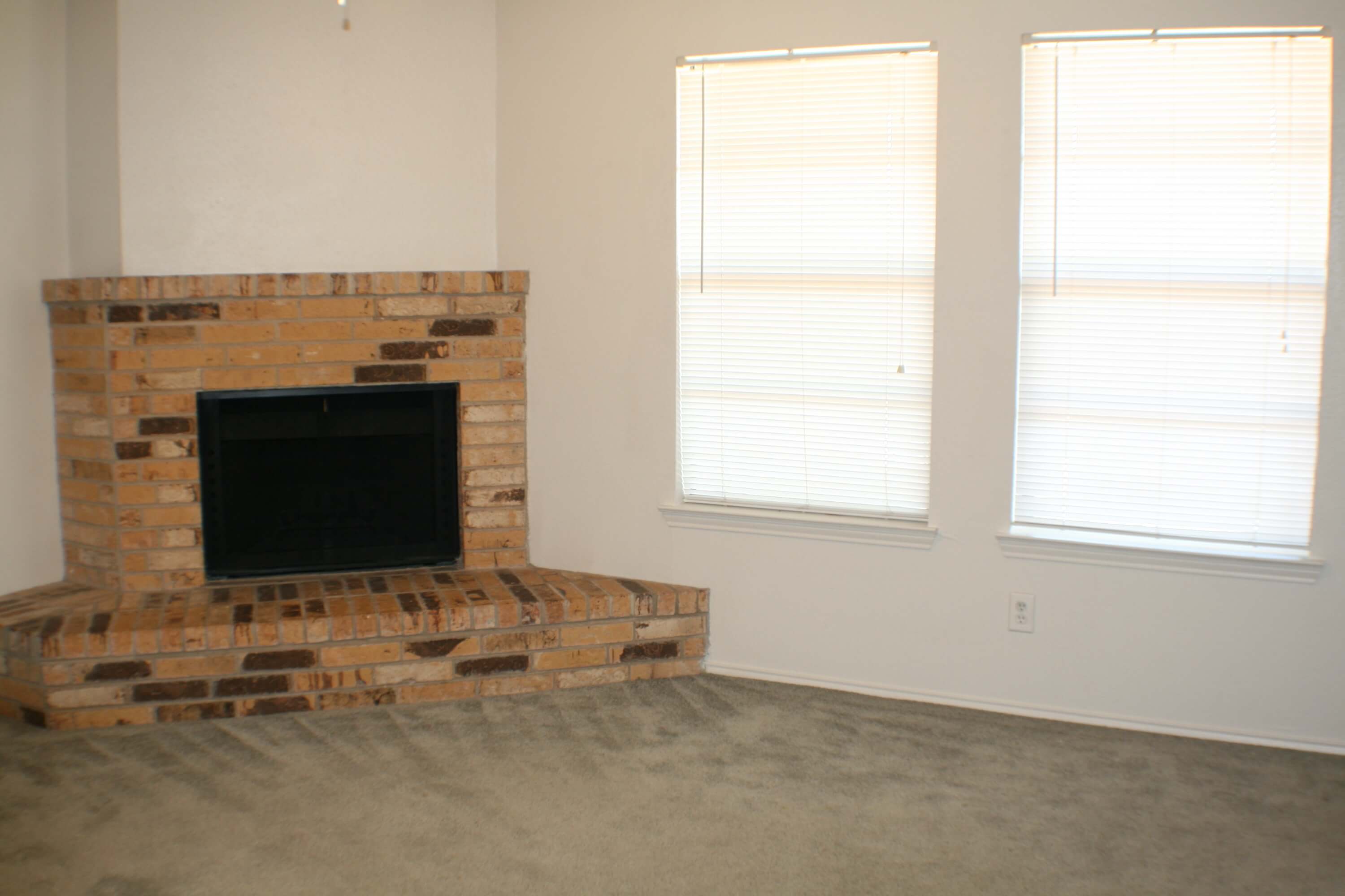 A living room featuring a brick fireplace at Stadium View Apartments.